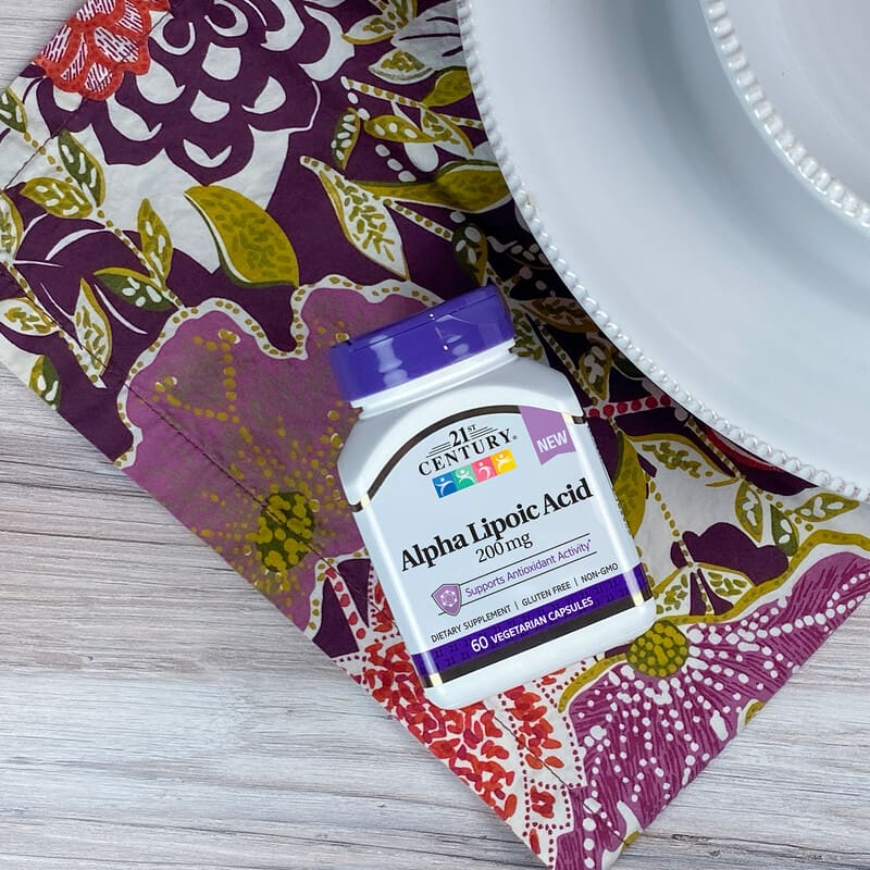 Supplement bottle labeled 'Alpha Lipoic Acid' on a patterned fabric background