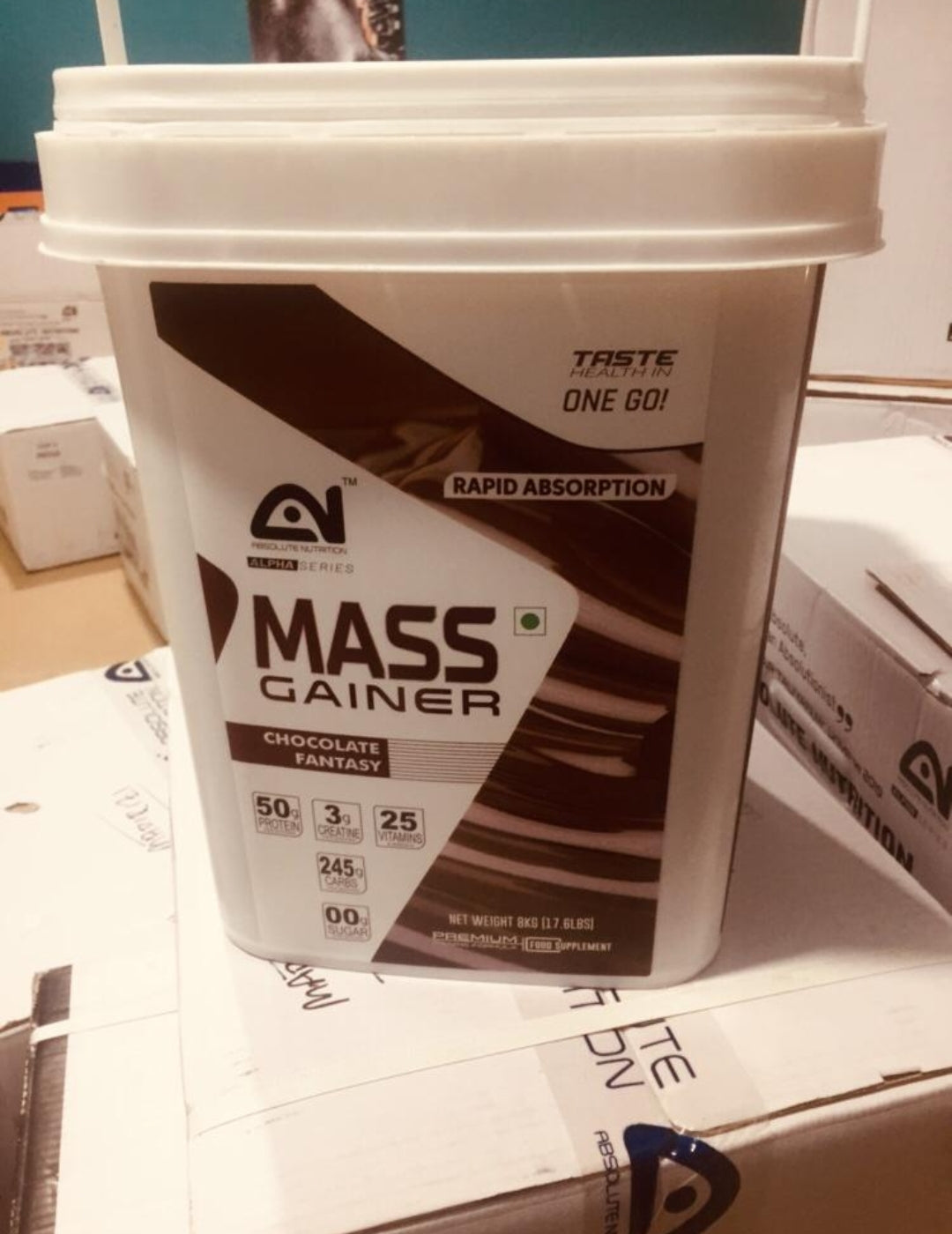 Mass gainer supplement container on a table with packaging in the background