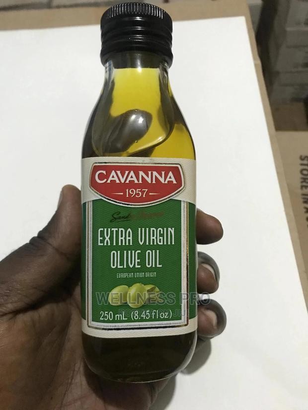 Bottle of Cavanna Extra Virgin Olive Oil held by a hand on a white surface