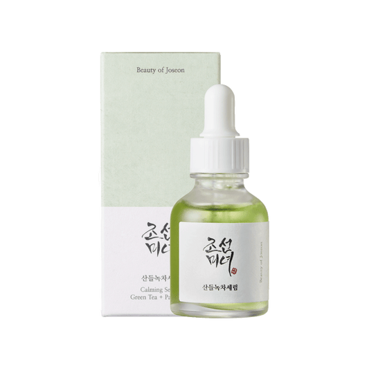 Skincare serum bottle with dropper and packaging on a green background