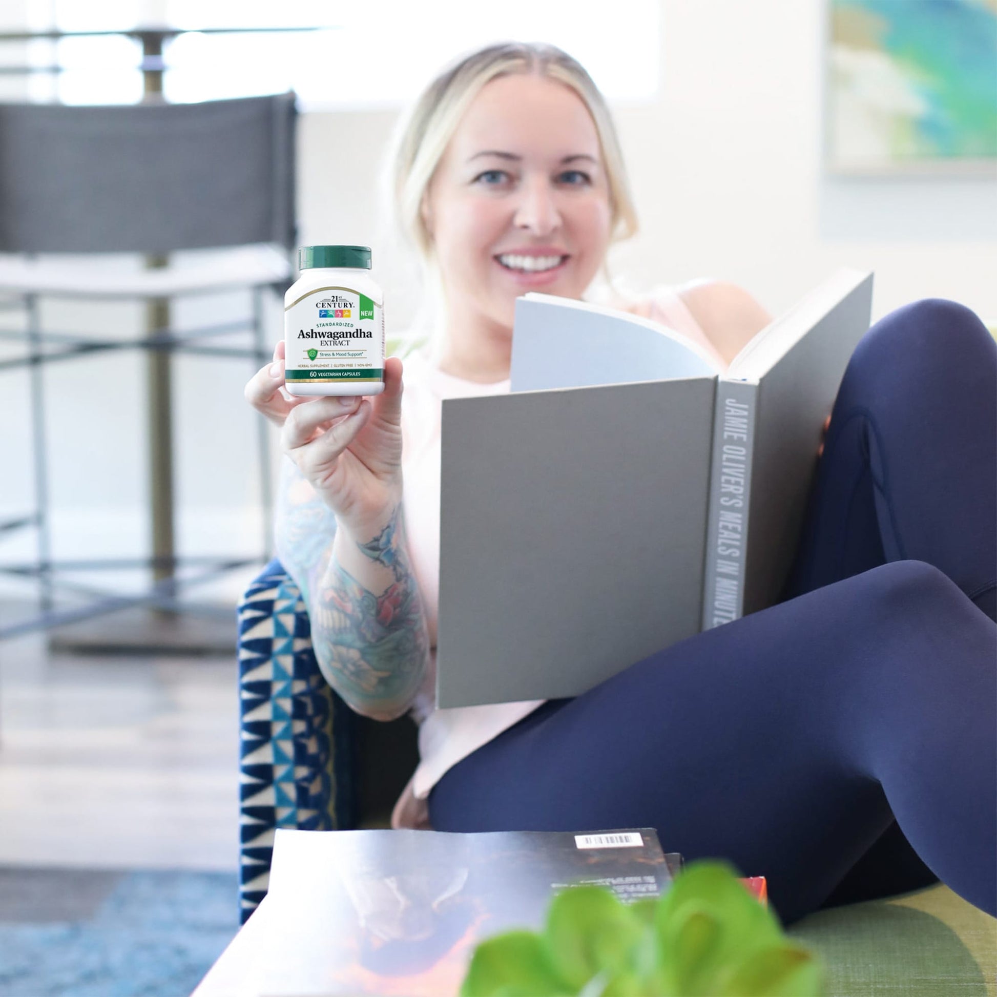 Woman holding a book and a bottle of supplements in a casual setting