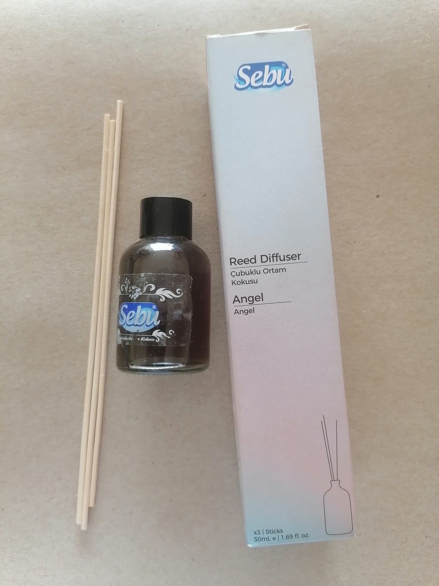Sebu reed diffuser set with bottle, sticks, and packaging on a beige background